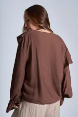 Blusa de color marrón con escote en V, mangas largas abullonadas con puños elásticos y detalles de volados en los hombros y el frente.