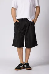 Bermuda sastrera baggy de color negro con diseño de rayas diplomáticas finas blancas. Cuenta con bolsillos laterales y presillas para cinturón.