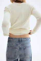 Jeans de cinco bolsillos en denim de algodón con leve stretch, tiro alto y cierre de botón. Corte ajustado de cintura a muslo, y pierna ancha (bootcut) desde la rodilla hasta el bajo. Presenta un lavado celeste medio con efecto desgastado.