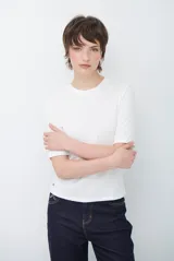 Remera básica de algodón color blanco, con cuello redondo y mangas que llegan hasta el codo.