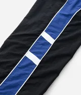 Pantalón deportivo de corte recto confeccionado en microfibra de poliamida, color negro con paneles laterales en color violeta y detalles en blanco. Cuenta con cintura elástica con cordón ajustable.