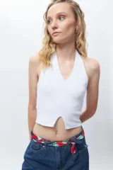 Crop top blanco de algodón, sin mangas, con cuello halter y abertura en el frente.