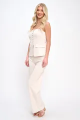 Conjunto de dos piezas compuesto por un top strapless con botones frontales y bolsillos decorativos, y un pantalón de corte recto y tiro alto. Confeccionado en tela con textura suave tipo gamuza.