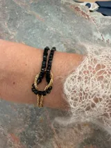 Pulsera de oro de 18k con diseño de cadena tipo serpiente doble y un nudo central decorativo. Cuenta con cierre de mosquetón y cadena de alargue con placa grabada.
