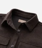 Camisa de corte largo tipo shacket, confeccionada en polivelour color marrón. Presenta cuello camisero, cierre frontal con botones, hombros caídos, mangas largas y dos bolsillos frontales aplicados con solapa.