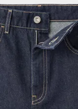 Pantalón de jean estilo barrel con diseño balloon, de tiro medio y corte holgado. Presenta cinco bolsillos, cierre frontal con cremallera y botón, y costuras en contraste.
