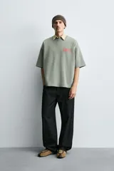 Sudadera de corte boxy fit, color verde oliva con efecto lavado. Presenta cuello redondo, manga corta terminada en rib y textos estampados a contraste en color rojo en el pecho.