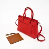 Cartera tipo tote de cuero sintético color rojo con doble asa corta y correa larga desmontable. Tiene un bolsillo externo con cierre y tirador de cuero.