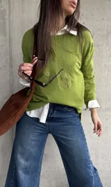 Sweater de punto color verde lima, de manga larga, con detalle de bordado en relieve con diseño floral en el frente.