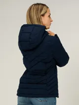 Campera ligera acolchada de Tommy Hilfiger en color azul marino. Presenta un diseño con cierre frontal de cremallera, cuello alto con capucha ajustable mediante cordones y dos bolsillos laterales con cierre. El diseño incluye costuras horizontales y diagonales que definen su estructura acolchada.