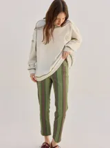 Buzo oversize color gris melange con corte crew, cuello redondo, mangas largas y detalles bordados en color verde en el cuello, puños y ruedo. Presenta el logo de la marca bordado en el pecho.