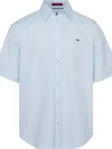 Camisa celeste de manga corta Tommy Hilfiger, confeccionada en algodón orgánico y nylon. Tiene cuello clásico, cierre frontal con botones, dobladillo curvo y logo bordado en el pecho.