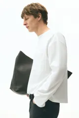 Remera de manga larga en punto pesado de algodón, color blanco, con cuello redondo ribeteado acanalado, hombros caídos, bolsillo superior abierto y bajo recto. Corte holgado.