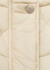 Campera acolchada de diseño oversize en color beige, con cuello alto, cierre frontal de cremallera y botones, y bolsillos laterales.