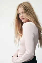 Remera corta de punto acanalado color rosado, con mangas largas, escote cuadrado ribeteado en encaje y una moña de satén en el centro.