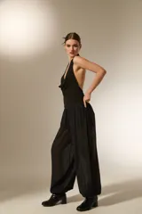 Pantalón tipo babucha de color negro, confeccionado en tela semitransparente con textura de rayas verticales y pequeños detalles en relieve. Presenta una cintura elástica cómoda y un corte holgado que se ajusta ligeramente en los tobillos.