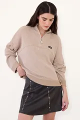 Sweater negro de punto con cuello alto y cierre frontal parcial de cremallera, de manga larga y diseño holgado con hombros caída.