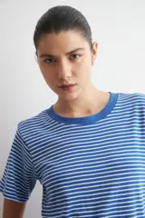 Remera de manga corta con diseño a rayas horizontales azules y blancas, y cuello redondo liso.