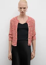 Chaqueta de punto con diseño calado y jaspeado en tonos rojizos y dorados. Presenta cuello redondo, cierre frontal con botones metálicos y mangas largas con terminaciones de canalé.