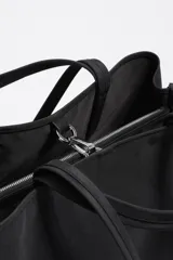 Bolso shopper de gran capacidad confeccionado en nylon color marrón, con estructura blanda, doble asa de mano y logo metálico de la marca en la parte frontal. Incluye cierre con mosquetón y bolsillo interior.