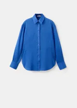 Camisa de ramio color azul eléctrico, de corte recto y largo, con cuello camisero, manga larga con puños abotonados, dos bolsillos de parche en el pecho y cierre frontal con botones.