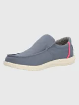 Alpargata slip-on Hush Puppies modelo Gordon, color azul grisáceo con detalle de costura lateral en color fucsia. Presenta suela de EVA moteada en tono crema y forro interior a rayas.