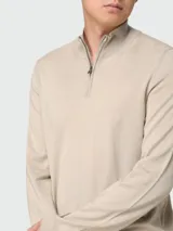Buzo de punto fino color beige, con cuello alto y cierre frontal parcial, de manga larga y diseño clásico.