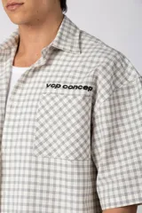 Camisa de manga corta de popelina con patrón a cuadros, calce boxy y largo a la cintura, con bolsillos y canesú cortados en diagonal.