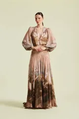 Vestido largo Natalia Antolin de gasa, con escote en V profundo, mangas largas abullonadas y puños ajustados con botones dorados. Presenta un estampado de paisaje campestre con caballos.