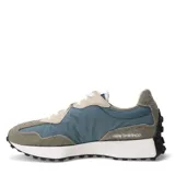 Championes urbanos New Balance modelo 327, con diseño retro inspirado en los años 70. Presentan una combinación de colores azul piedra, beige y blanco, con el logo N característico en el lateral, confeccionados en una mezcla de gamuza y nylon con suela de goma dentada.