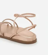 Sandalia plana color dorado con acabado metalizado, diseño de tiras finas, algunas de ellas con incrustaciones de brillo, y cierre ajustable con hebilla al tobillo.