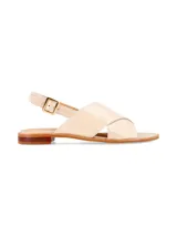 Sandalia plana de cuero beige con tiras anchas cruzadas en el empeine, tira trasera con hebilla metálica ajustable y suela baja con pequeño tacón.