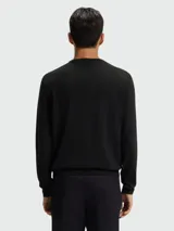 Buzo de punto fino con cuello redondo y mangas largas, confeccionado en lana virgen. Presenta un diseño minimalista con el logo de la marca bordado discretamente en el pecho.