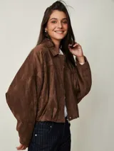 Campera marrón de gamuza sintética con cierre frontal, cuello camisero, hombros caídos y mangas amplias.