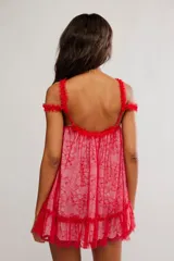 Vestido corto de tul bordado color rojo y rosado, con escote recto, volados sobre los hombros, tiras finas regulables y ruedo terminado en volado. Caída suelta y liviana.