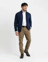 Cardigan de punto gris con cuello alto, cierre frontal de metal con doble cursor y bolsillos laterales. Presenta puños y cuello en tejido canalé.