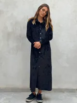 Vestido camisero largo de terciopelo negro con botones frontales y cuello camisero.