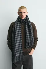 Bufanda de tejido suave con diseño de cuadros vichy en tonos gris y azul marino, terminada con flecos en los extremos.