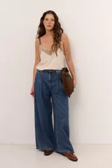 Jean de denim azul de corte wide leg, tiro alto con pinzas en la cintura y cierre frontal.