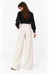 Pantalón de lino natural de tiro alto, corte wide leg y pinzas en la parte delantera. Cuenta con un pequeño bolsillo lateral con tapa y botón decorativo en la pretina.