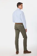 Pantalón de gabardina color marrón claro, corte slim fit, con bolsillos laterales y traseros. Se ajusta a la cintura con cinturón de cuero marrón.