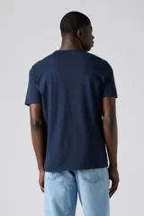 Remera de algodón de corte estándar con cuello redondo y manga corta. Presenta un diseño liso en color azul marino con un pequeño logo bordado en el pecho.