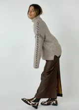 Falda midi color plateado metalizado, de corte recto con tajo en la espalda. Presenta detalles de costura que simulan bolsillos traseros.