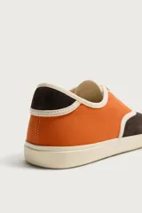 Zapatilla casual de hombre con diseño combinado en color naranja y marrón oscuro, con cordones y suela de goma en contraste.