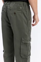 Pantalón cargo color tostado de corte amplio, con cintura elástica y cordón ajustable. Cuenta con bolsillos laterales con tapa en las piernas y puños elastizados en los tobillos.
