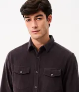 Camisa de hombre de corte regular confeccionada en terciopelo de algodón, con cuello clásico, cierre frontal de botones y dos bolsillos con solapa en el pecho.