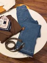 Jean de corte recto y tiro medio, confeccionado en denim azul oscuro con doble lycra. Presenta un diseño con ruedo deshilachado y costuras reforzadas.