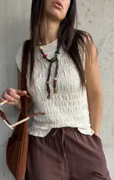 Blusa de punto sin mangas en color natural, con textura fruncida en todo el diseño y cuello redondo.