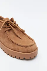 Zapato de gamuza color marrón con cordones, puntera con costura marcada y suela robusta dentada.