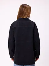 Campera de jean de corte oversize, color azul lavado, con cierre frontal de botones metálicos, bolsillos frontales con solapa en el pecho y bolsillos laterales inferiores.